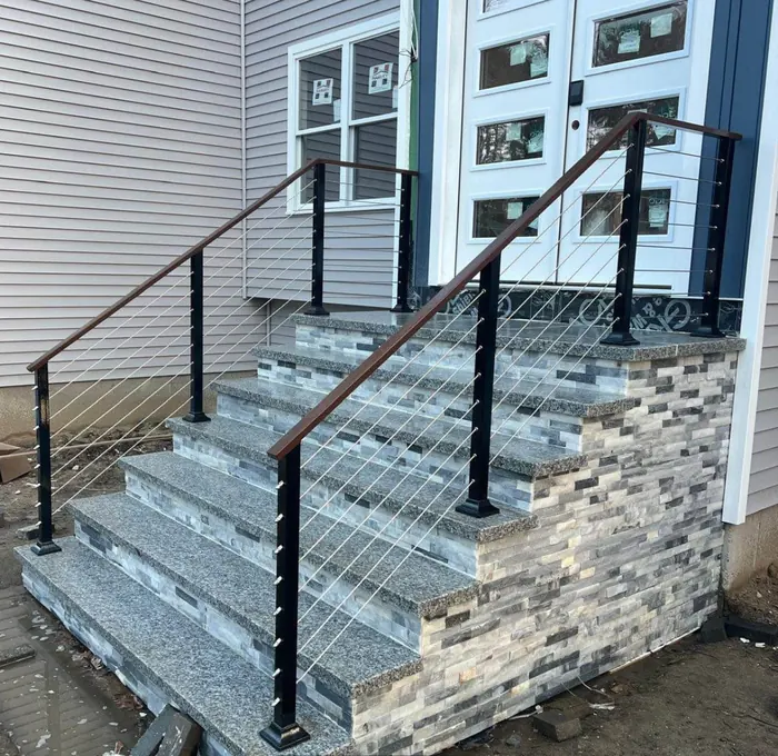 Cable railing with wood top rail on stacked-stone and granite steps