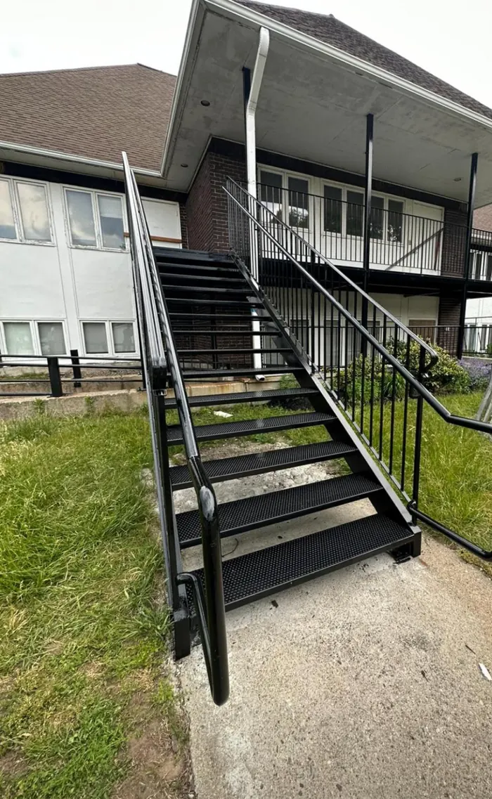 Exterior structural steel staircase with grated treads on a two-story commercial building